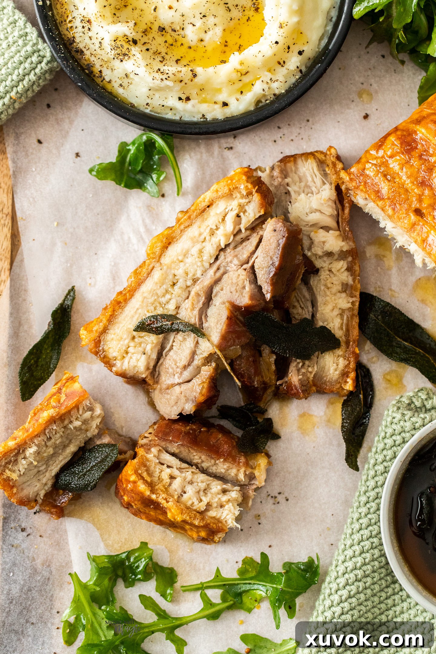 Two perfectly roasted slices of pork belly with crispy crackling on a wooden tray.