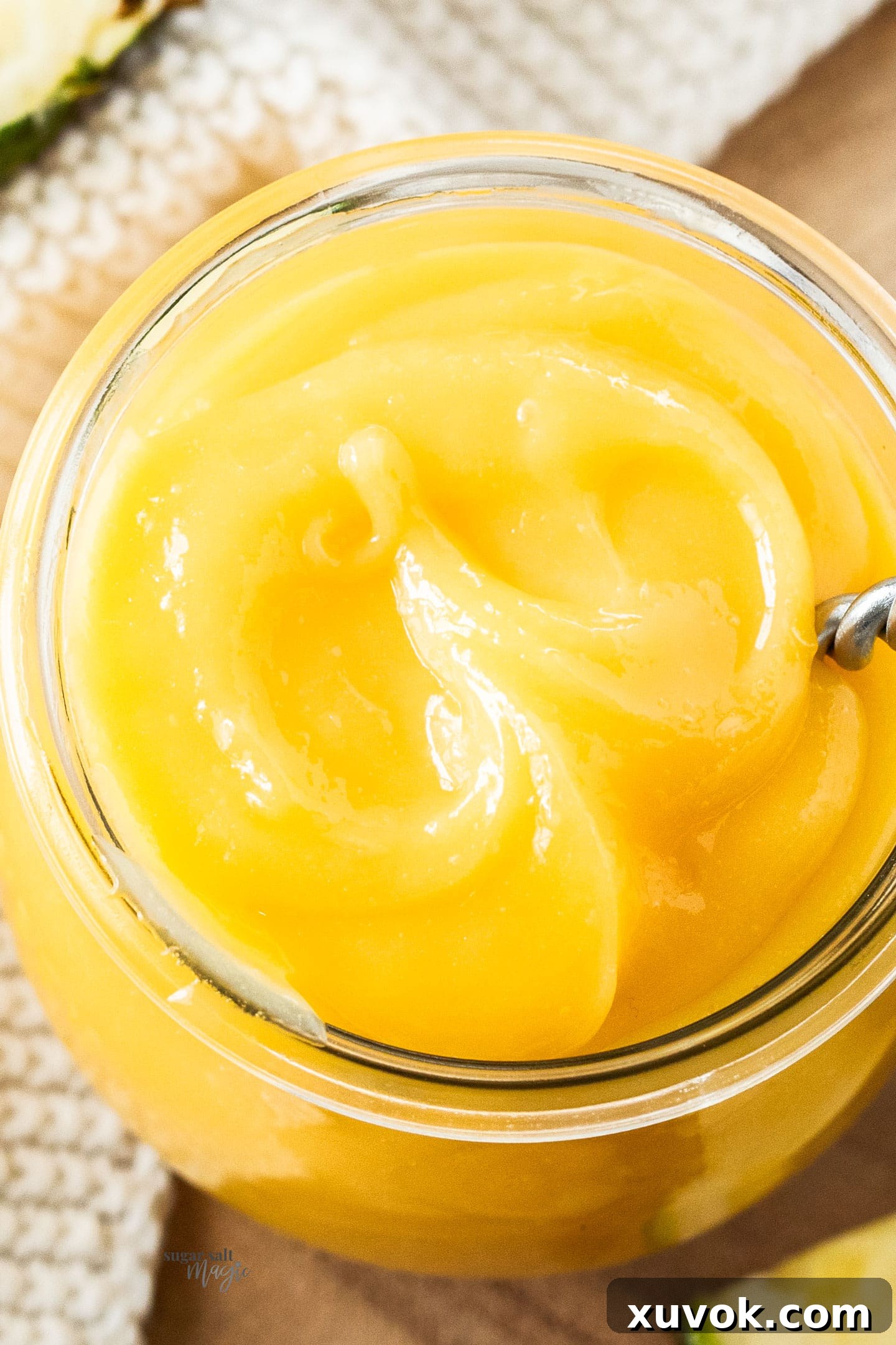 Top down view of a large jar filled with pineapple curd, emphasizing its creamy texture.