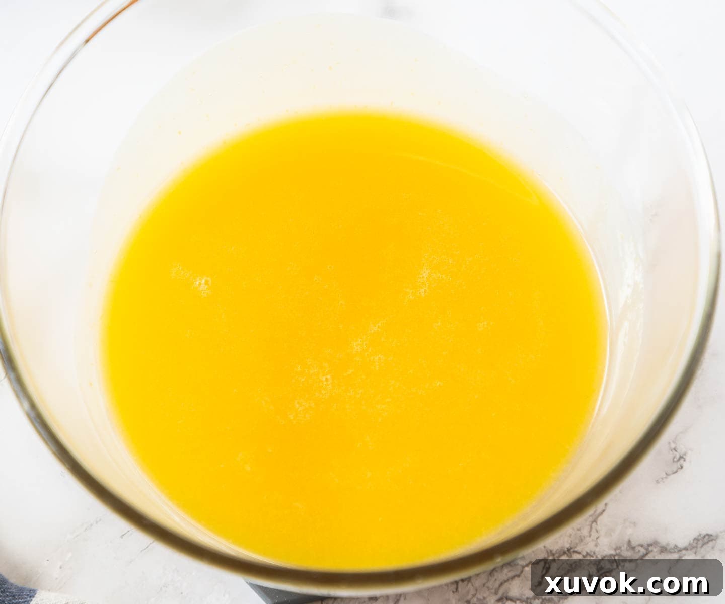 The beautifully strained, smooth pineapple curd resting in a clear bowl after straining.