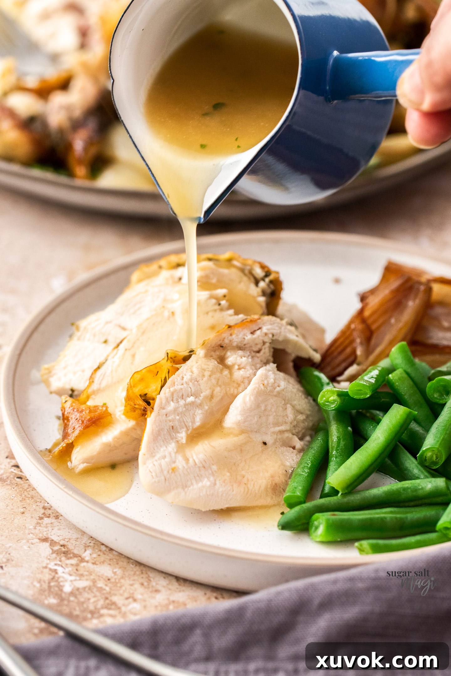 Carved chicken breast on a plate with gravy being poured over, highlighting its juiciness.