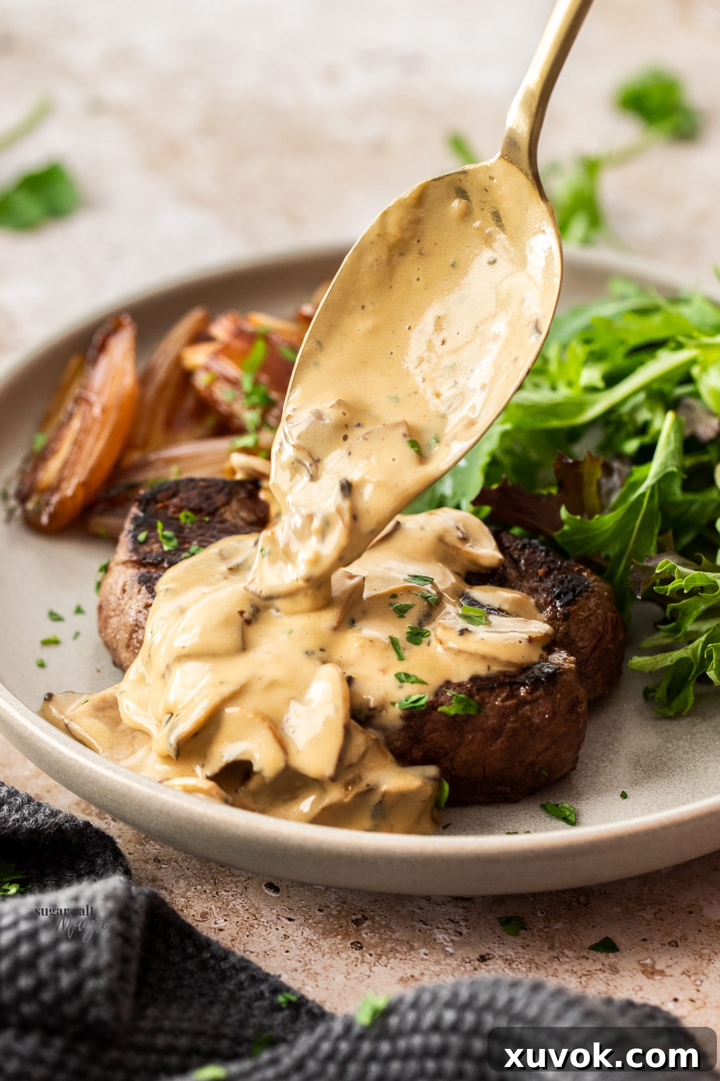 A perfectly cooked steak being generously covered with rich creamy mushroom sauce, highlighting its appeal.