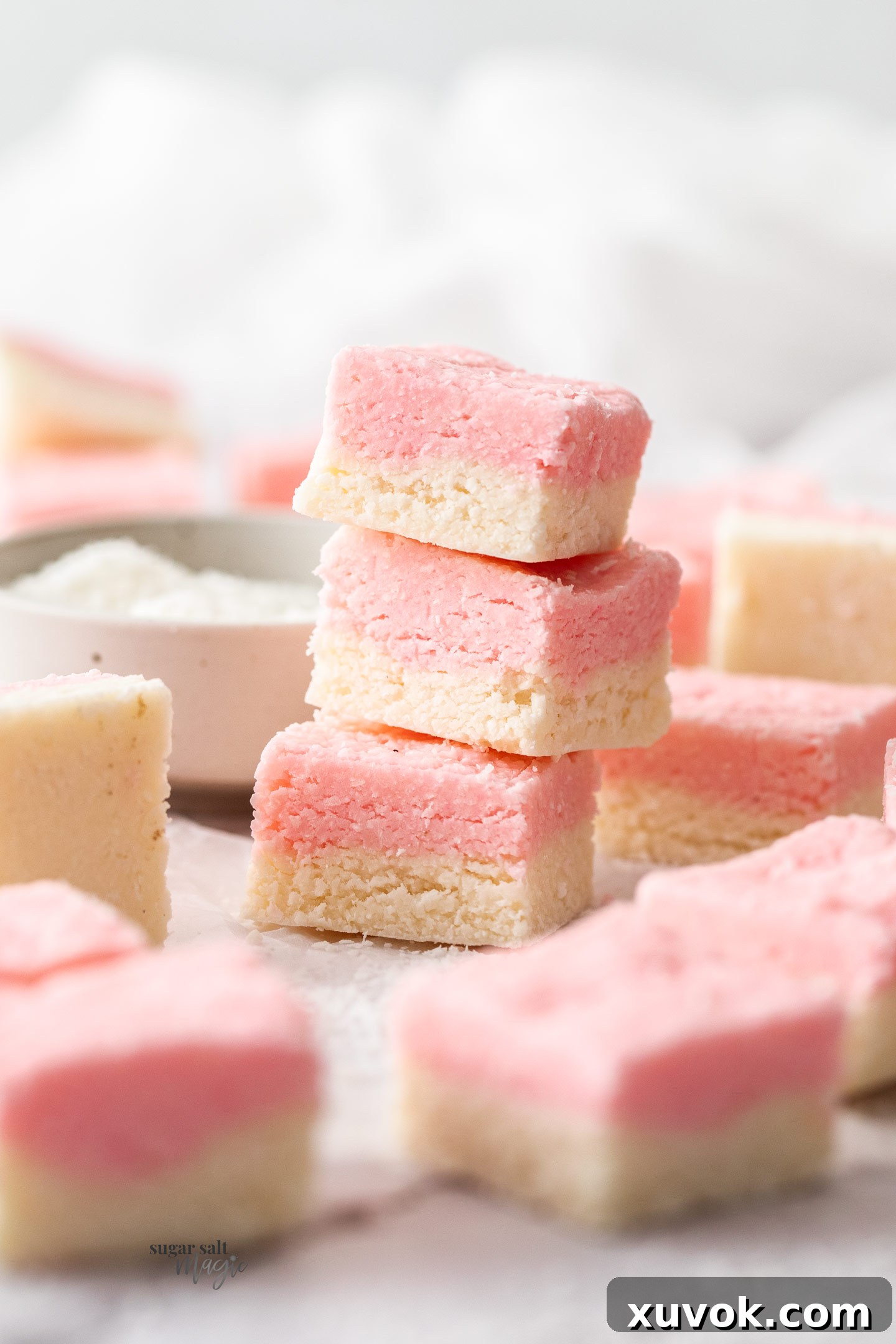 A stack of 3 coconut ice squares, showcasing the distinct pink and white layers.