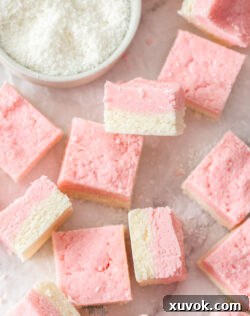 A batch of coconut ice squares on a marble benchtop.
