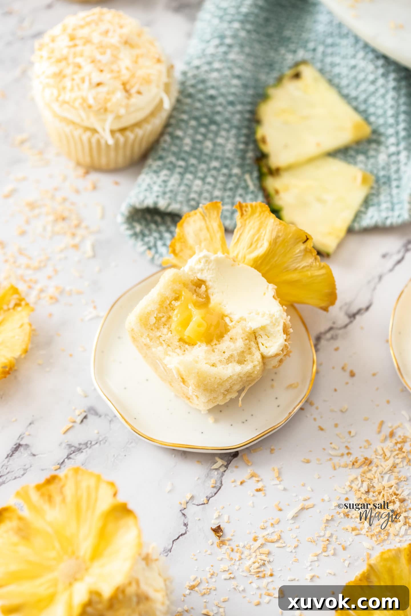 A close-up, artistic shot of a pineapple coconut cupcake, revealing its moist interior and the creamy pineapple curd filling, with a subtle toasted coconut topping.
