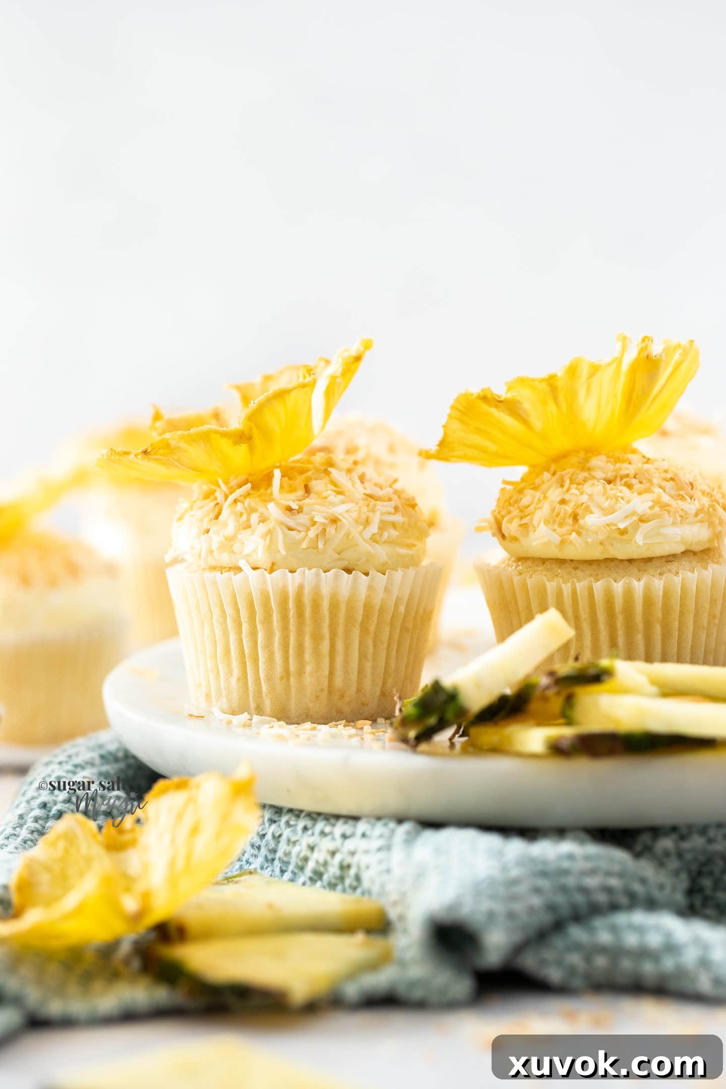 Another close-up of a pineapple coconut cupcake, showcasing its toasted coconut coating and delicate pineapple flower, ready to be enjoyed.
