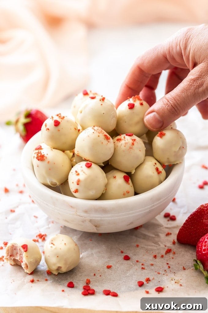 A hand picking up a white chocolate truffle in a small white bowl