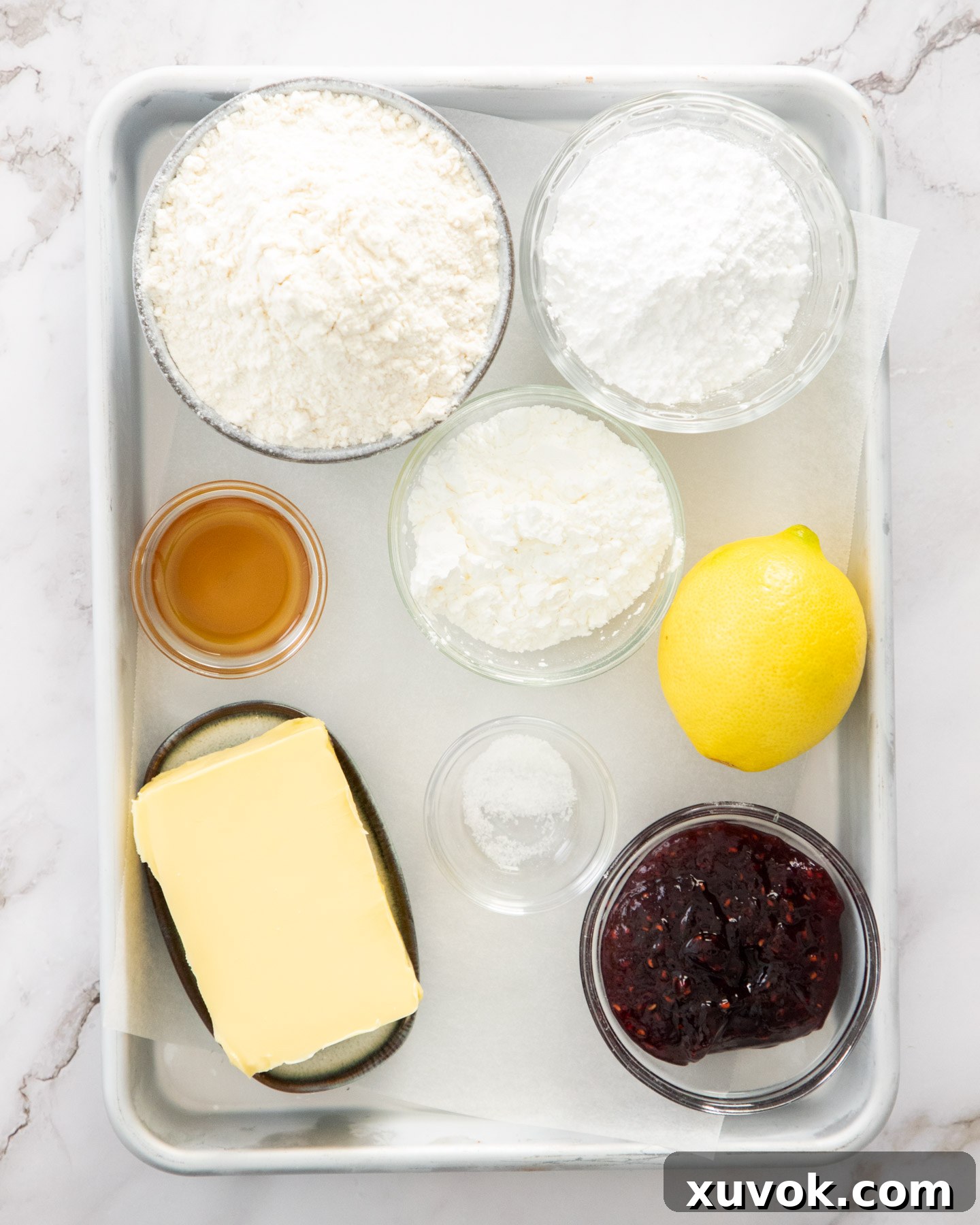 Ingredients for raspberry thumbprint cookies on a baking tray.