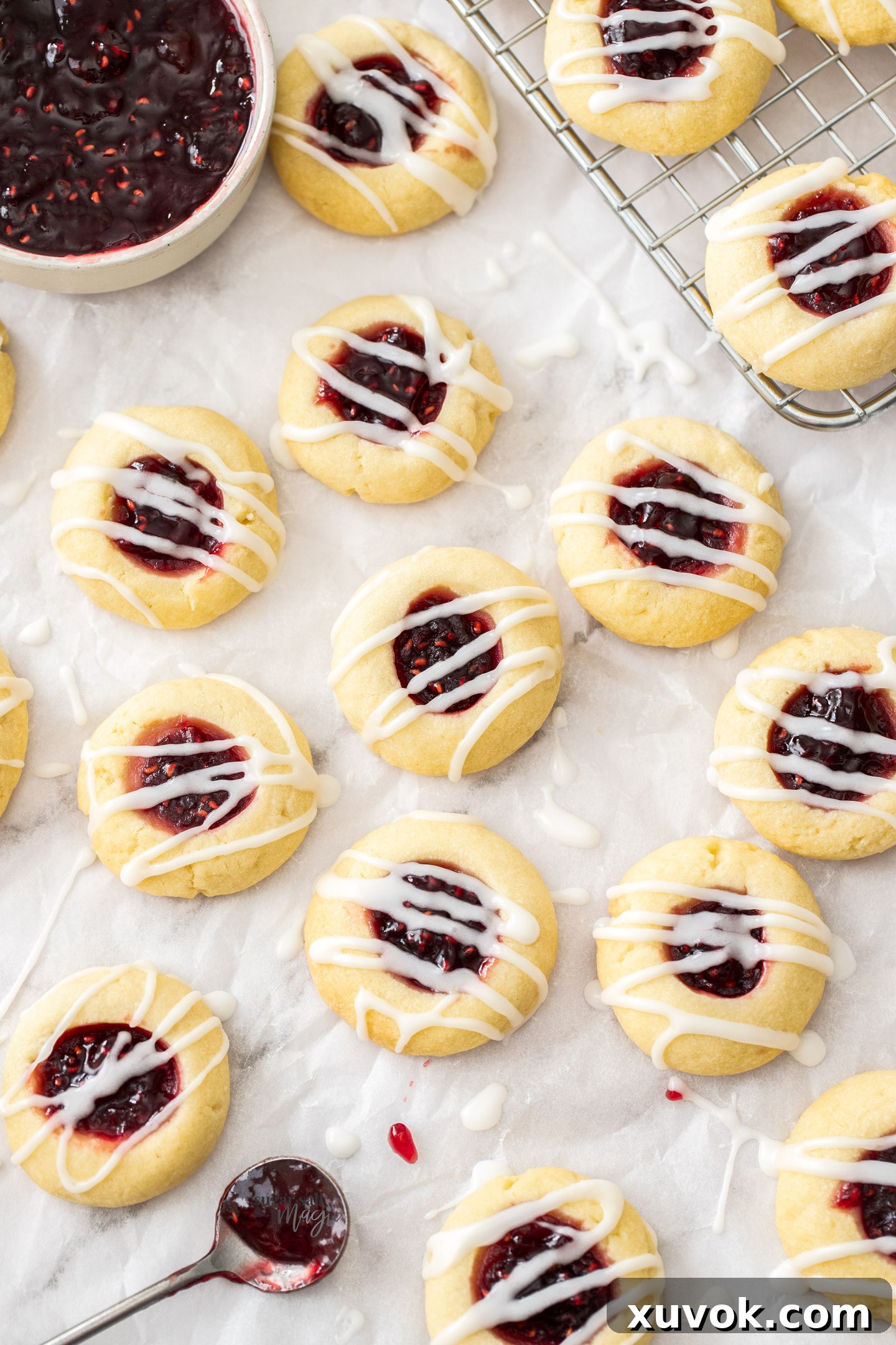 A batch of thumbprint cookies on a sheet of baking paper.