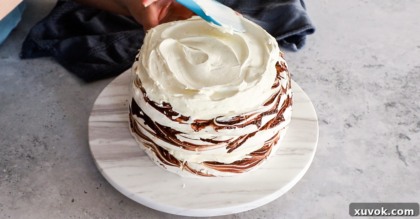 A meringue cake being assembled on a marble platter.