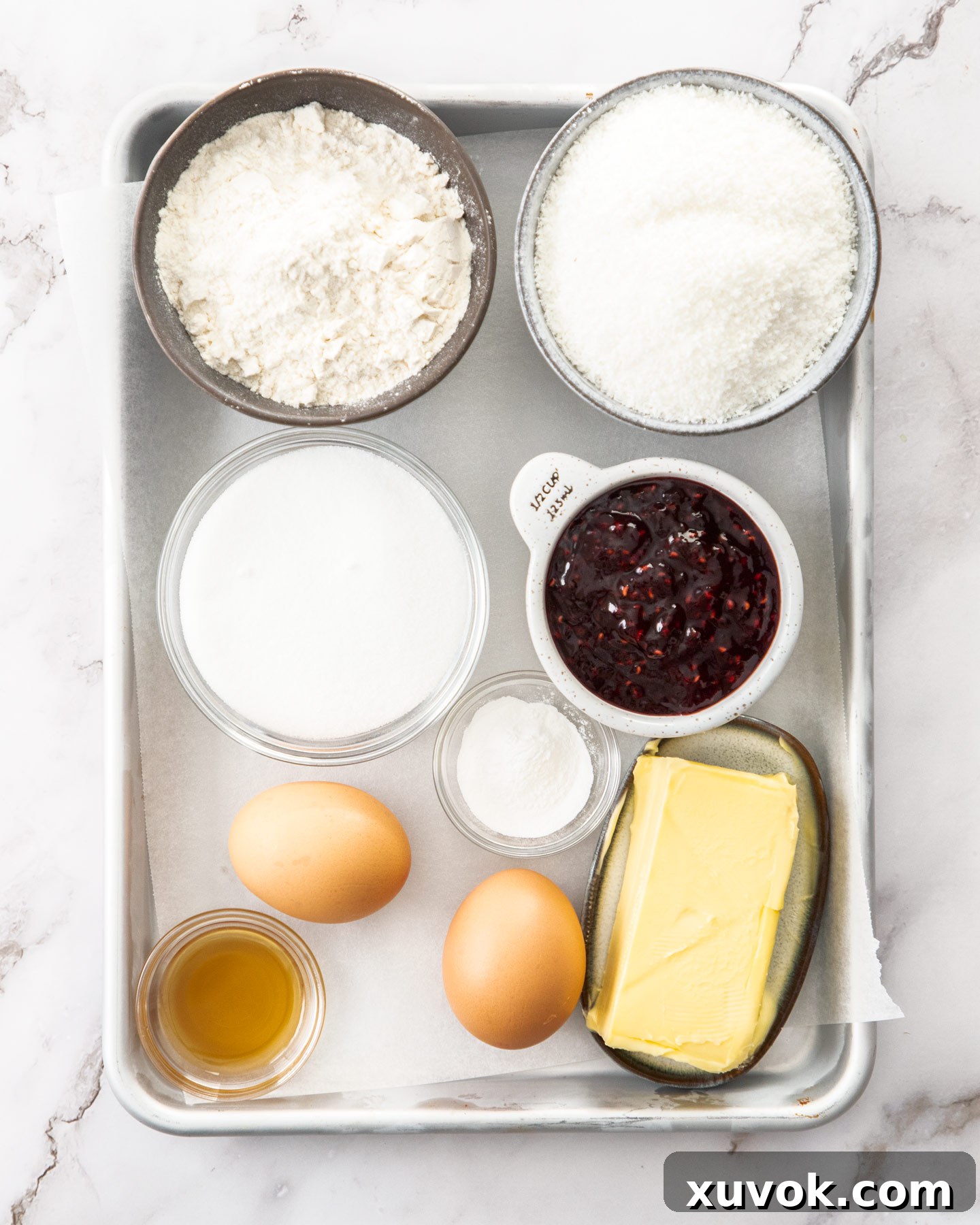 Ingredients for raspberry coconut slice laid out on a baking tray, ready for preparation.