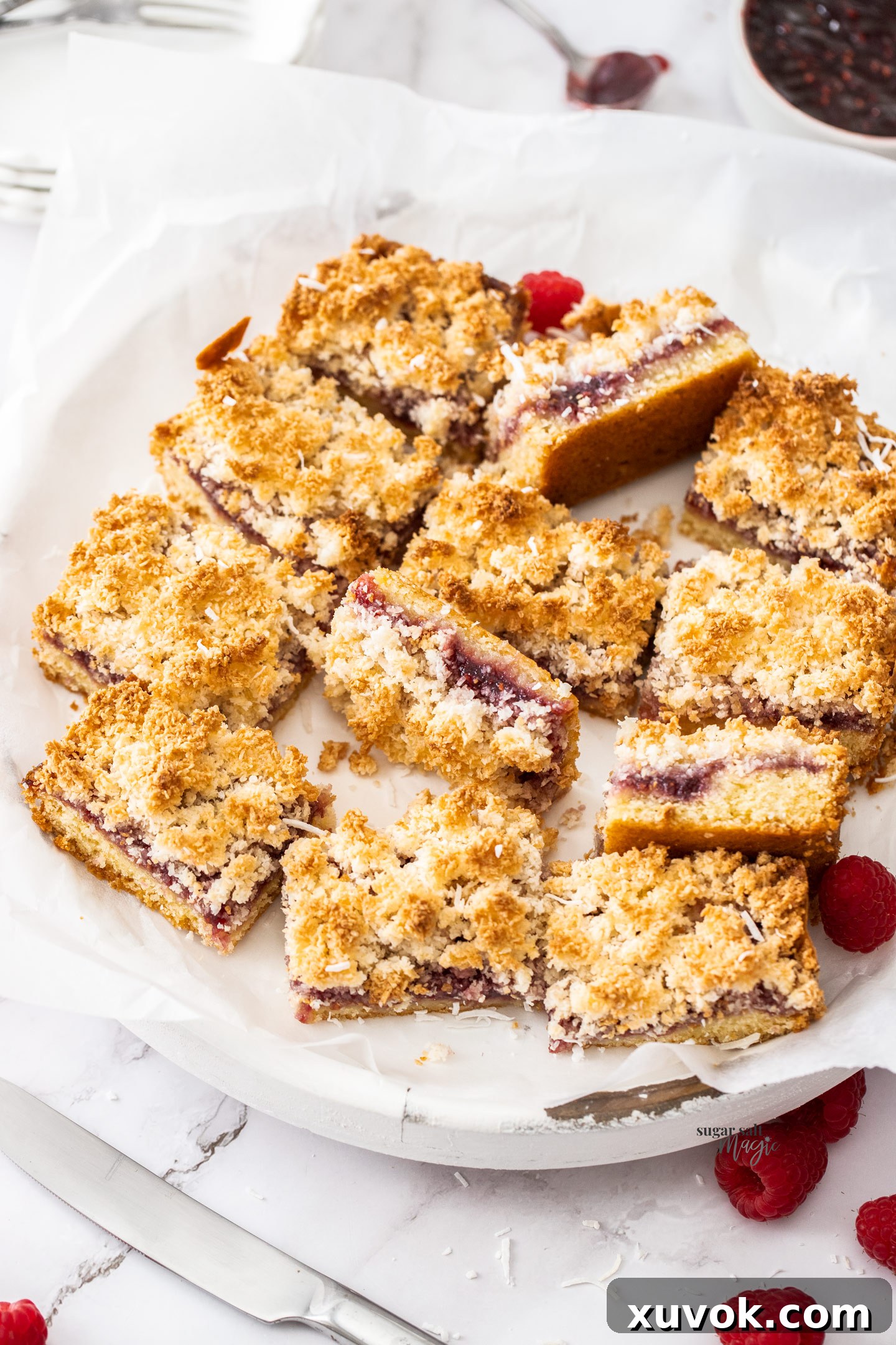 Pieces of raspberry coconut slice artfully arranged on a white platter, ready to be served.