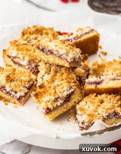 A pile of raspberry coconut slice on a platter, showcasing its golden topping and distinct layers.