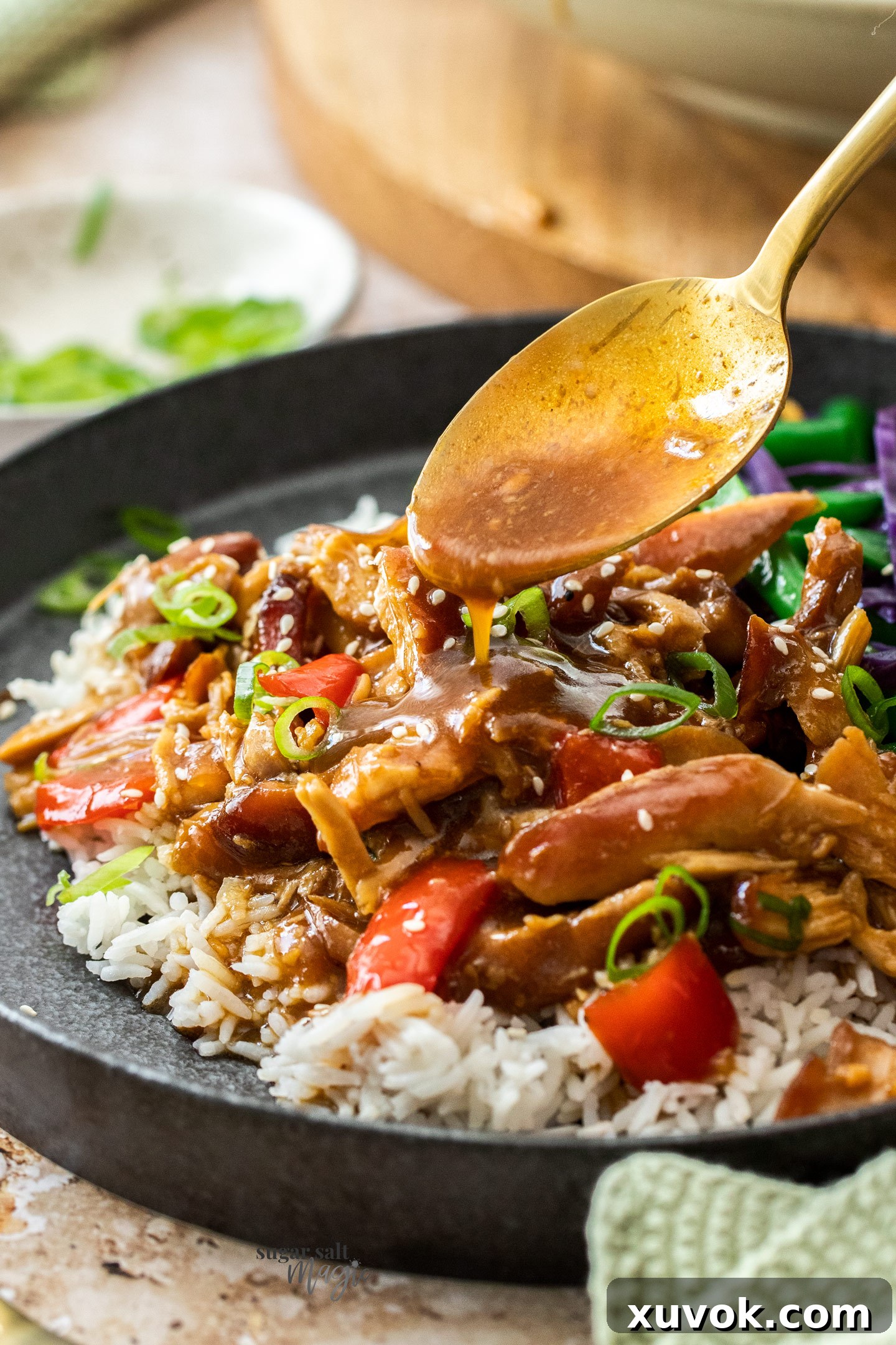 A spoon dribbling sauce onto chicken on a plate.