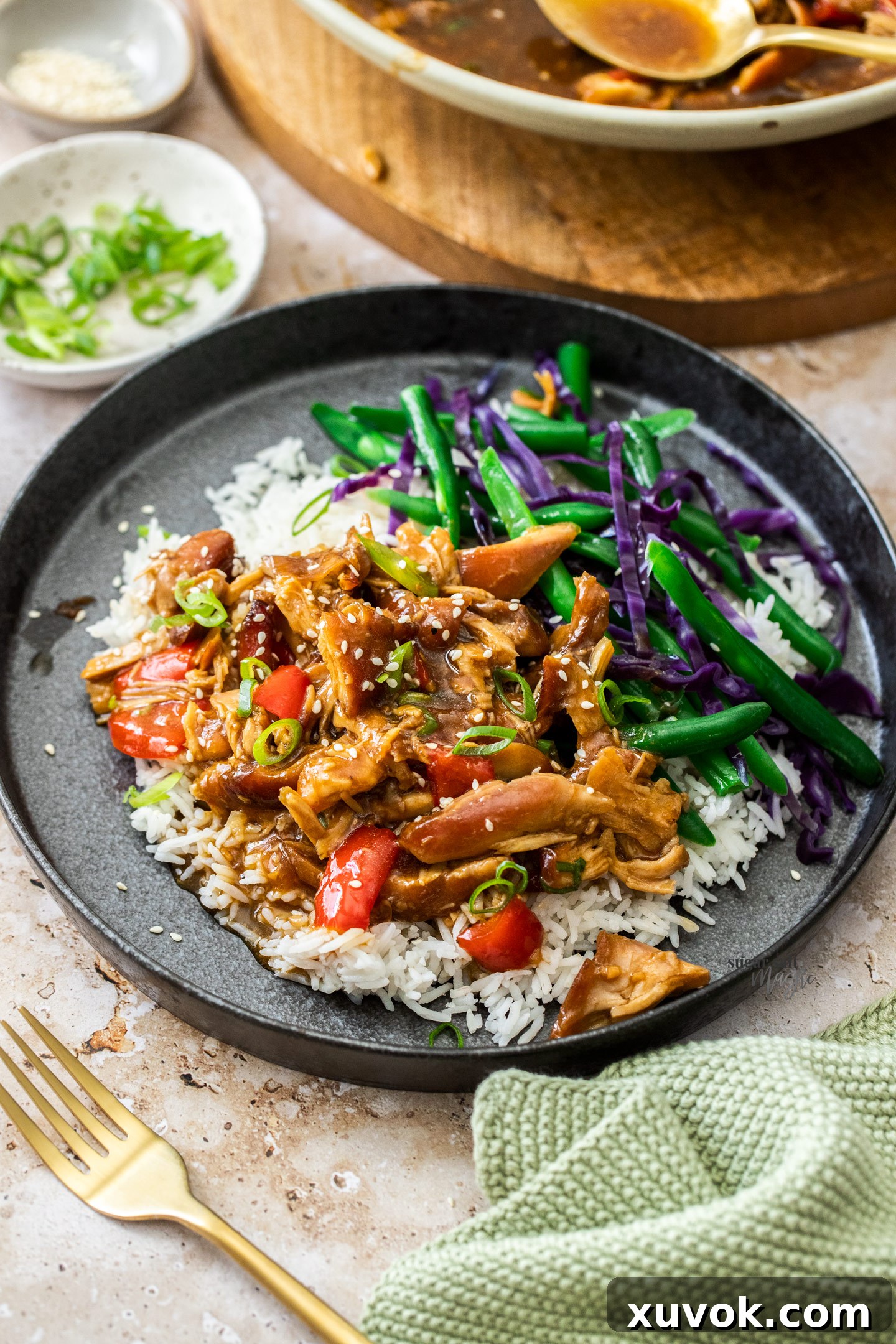 Slow cooker honey soy chicken over rice on a plate with beans on the side.