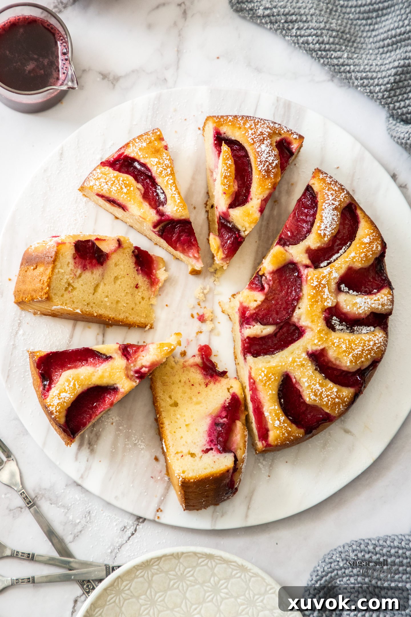 Top down view of a cake on a marble platter, cut into slices.