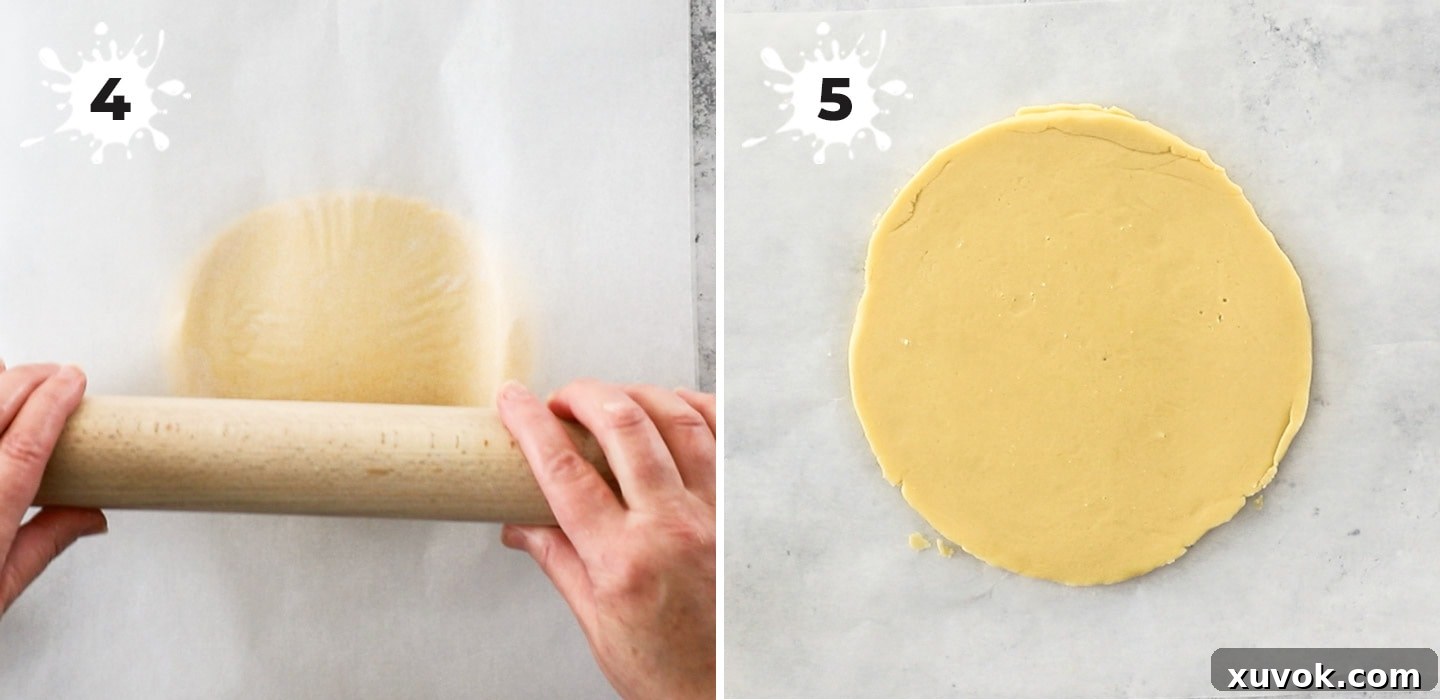 A close-up view of shortbread dough being rolled out between two sheets of baking paper.