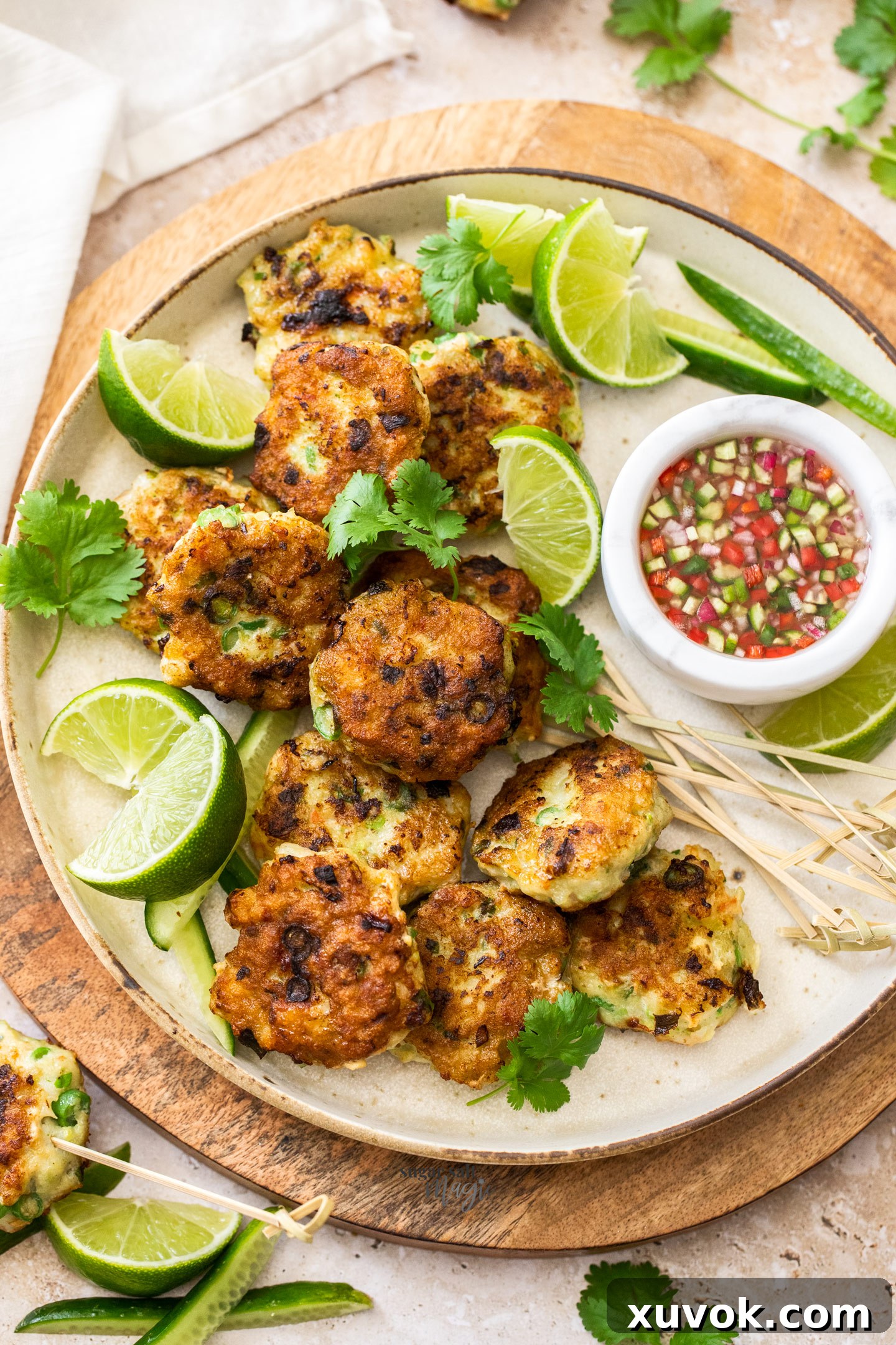 A batch of Thai fish cakes on a platter with sauce.