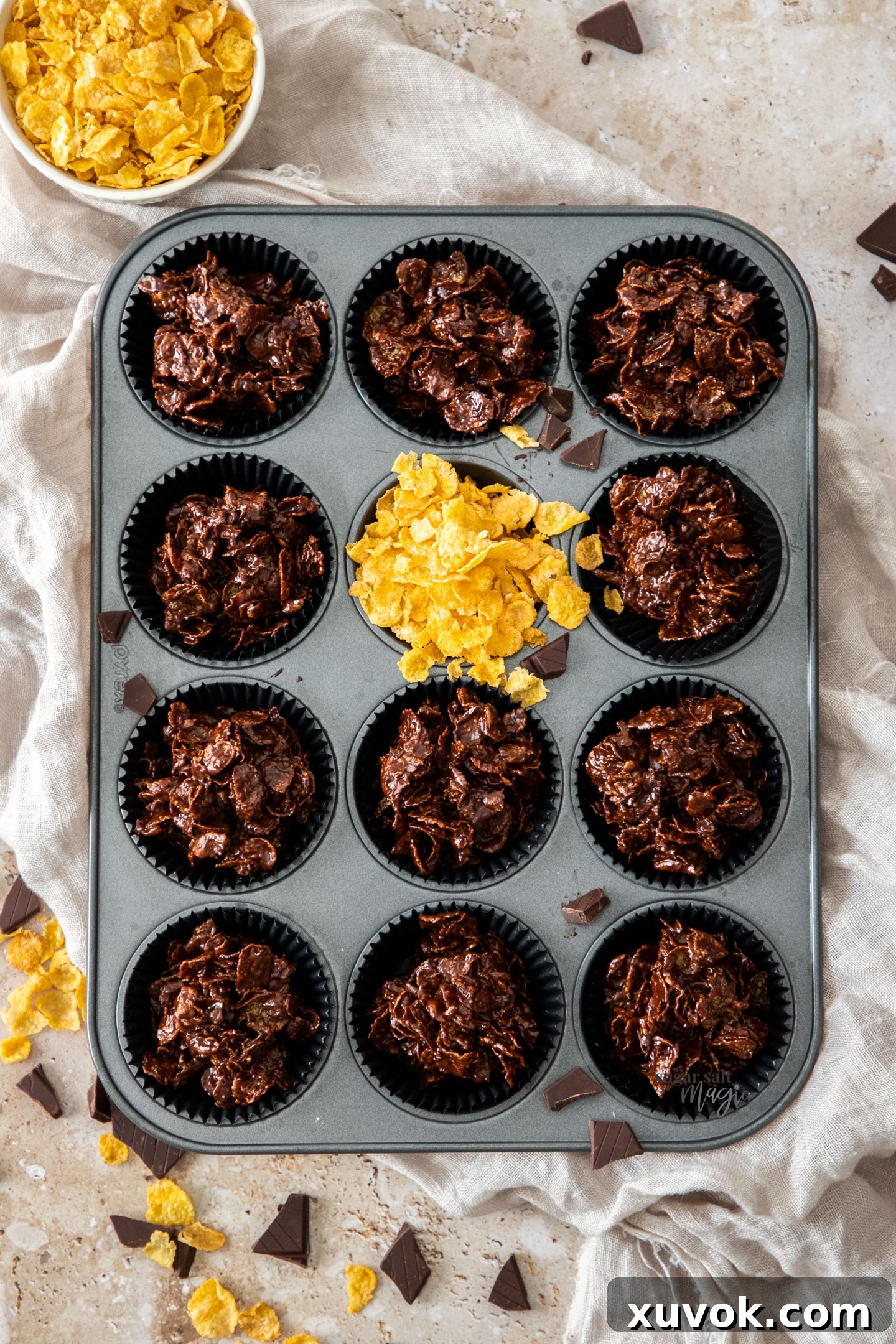 11 chocolate cornflake cakes in a muffin tray.