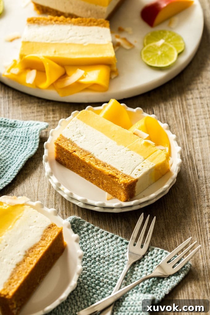 Slices of mango coconut cheesecake on white plates, with forks around and slices of lime.