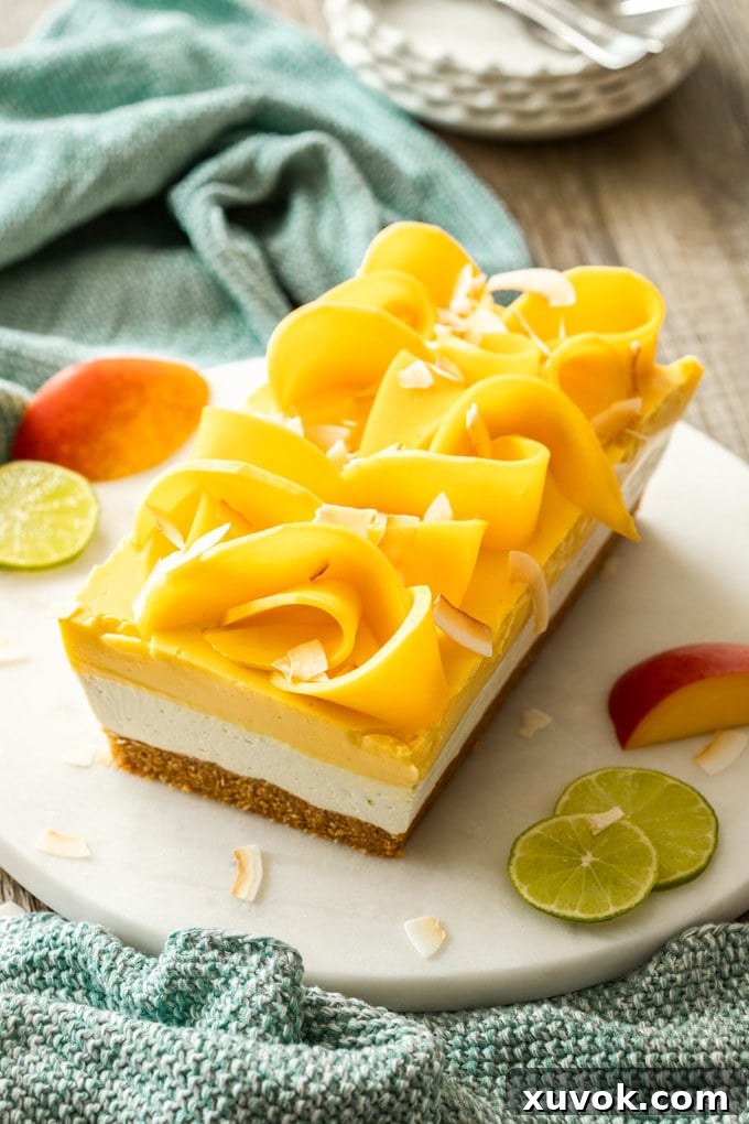 A dessert with 3 layers in a loaf shape on a marble cake plate. Topped with slices of mango.
