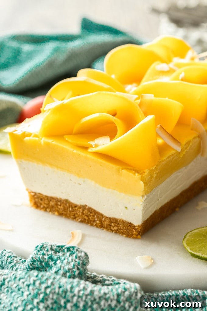 Close up of a 3-layer dessert topped with slices of mango and coconut chips.
