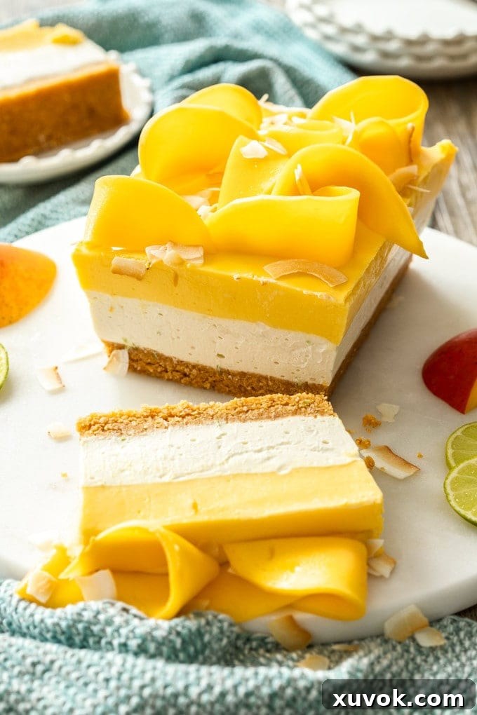 A dessert with 3 layers in a loaf shape on a marble cake plate. Topped with slices of mango.