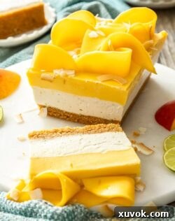 A dessert with 3 layers in a loaf shape on a marble cake plate. Topped with slices of mango.