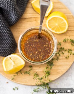 Top down view of marinade in a jar with lemons and thyme around it.