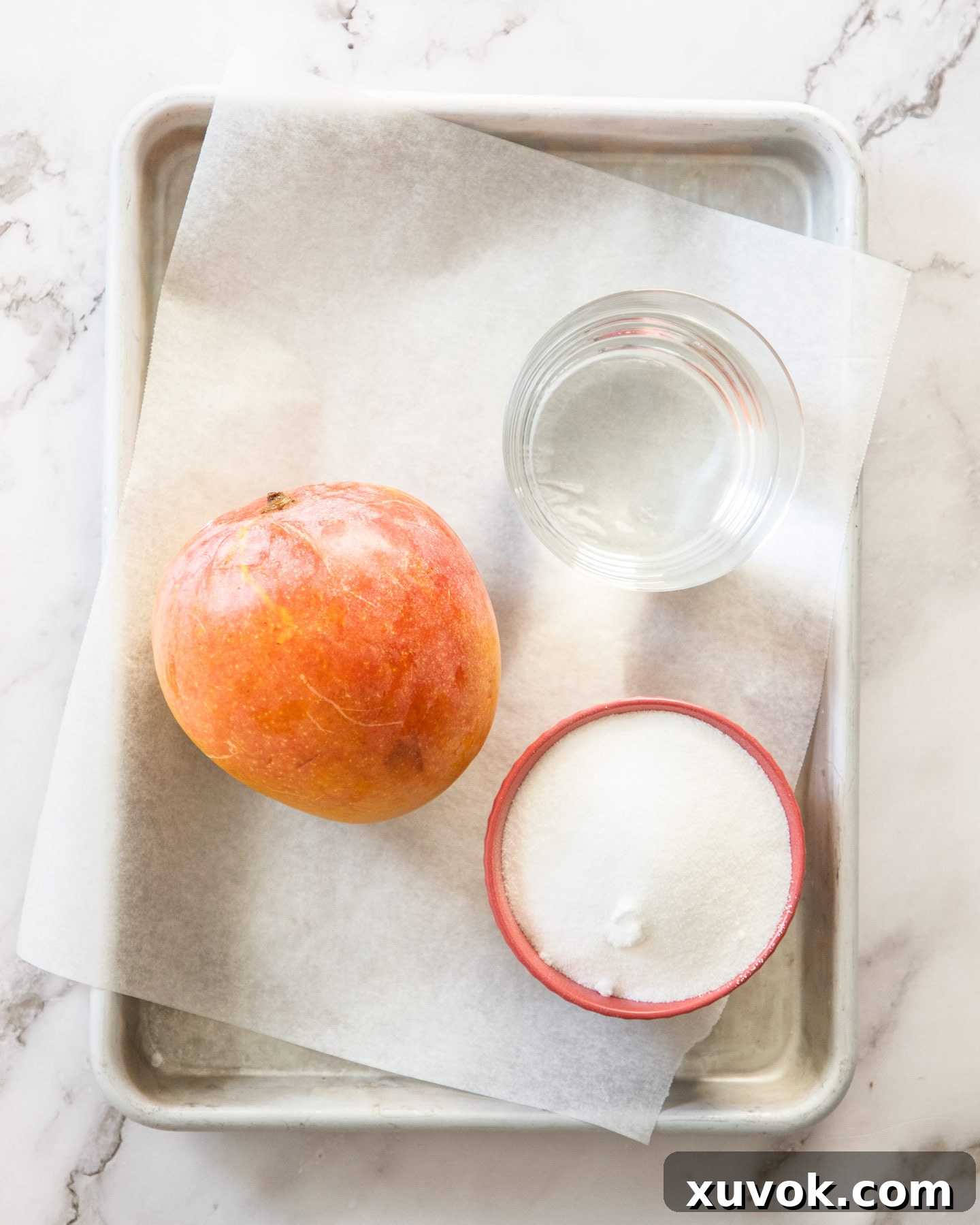 Fresh ingredients for mango syrup laid out on a baking tray, showcasing simplicity.