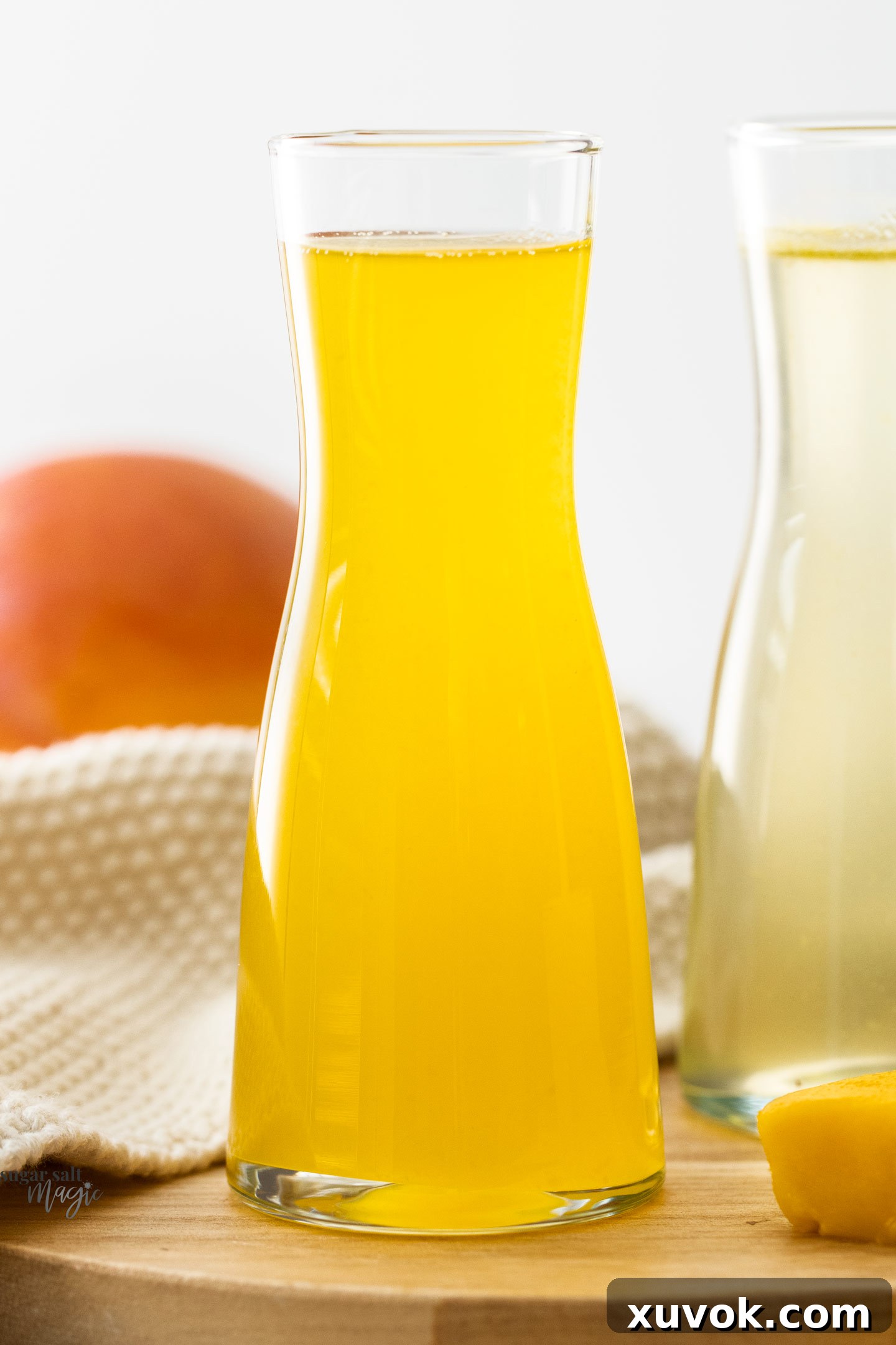 Close-up of a mini carafe brimming with bright yellow mango syrup, highlighting its luscious texture.