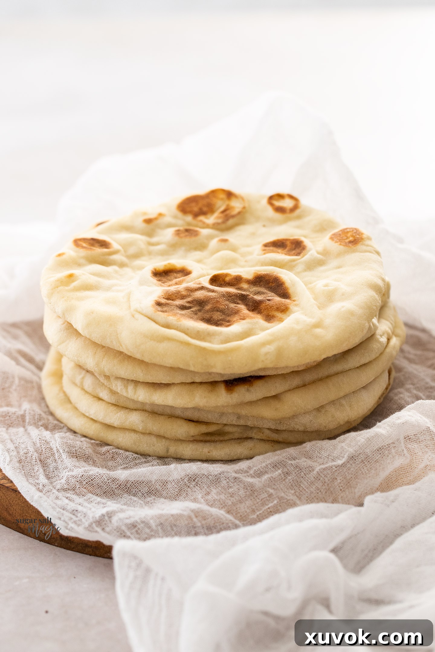 A stack of 6 flatbreads on a wooden board.