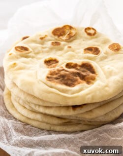 A stack of 6 flatbreads on a wooden board.