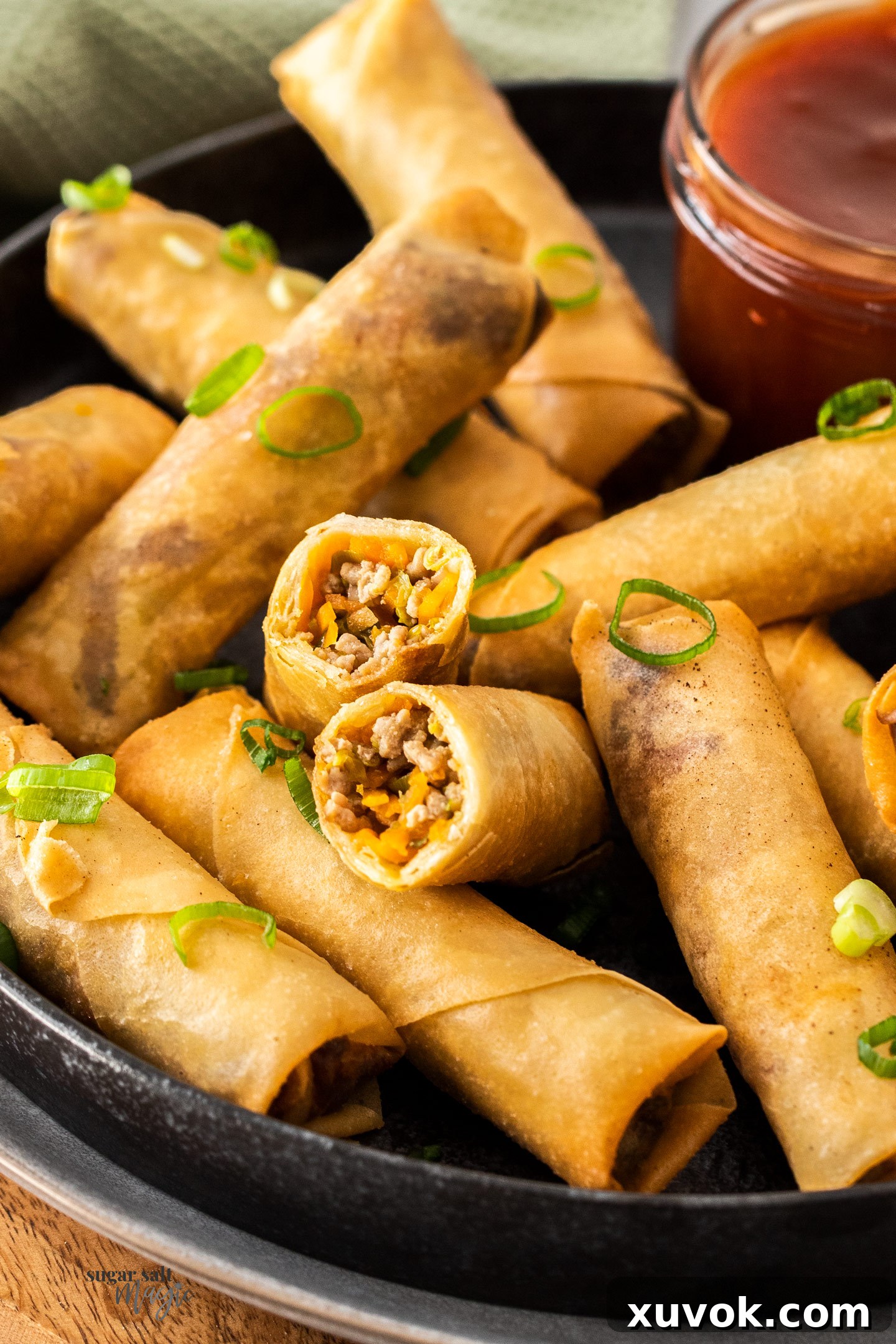 A perfectly cooked Chinese spring roll cut in half, revealing the savory pork and vegetable filling inside.
