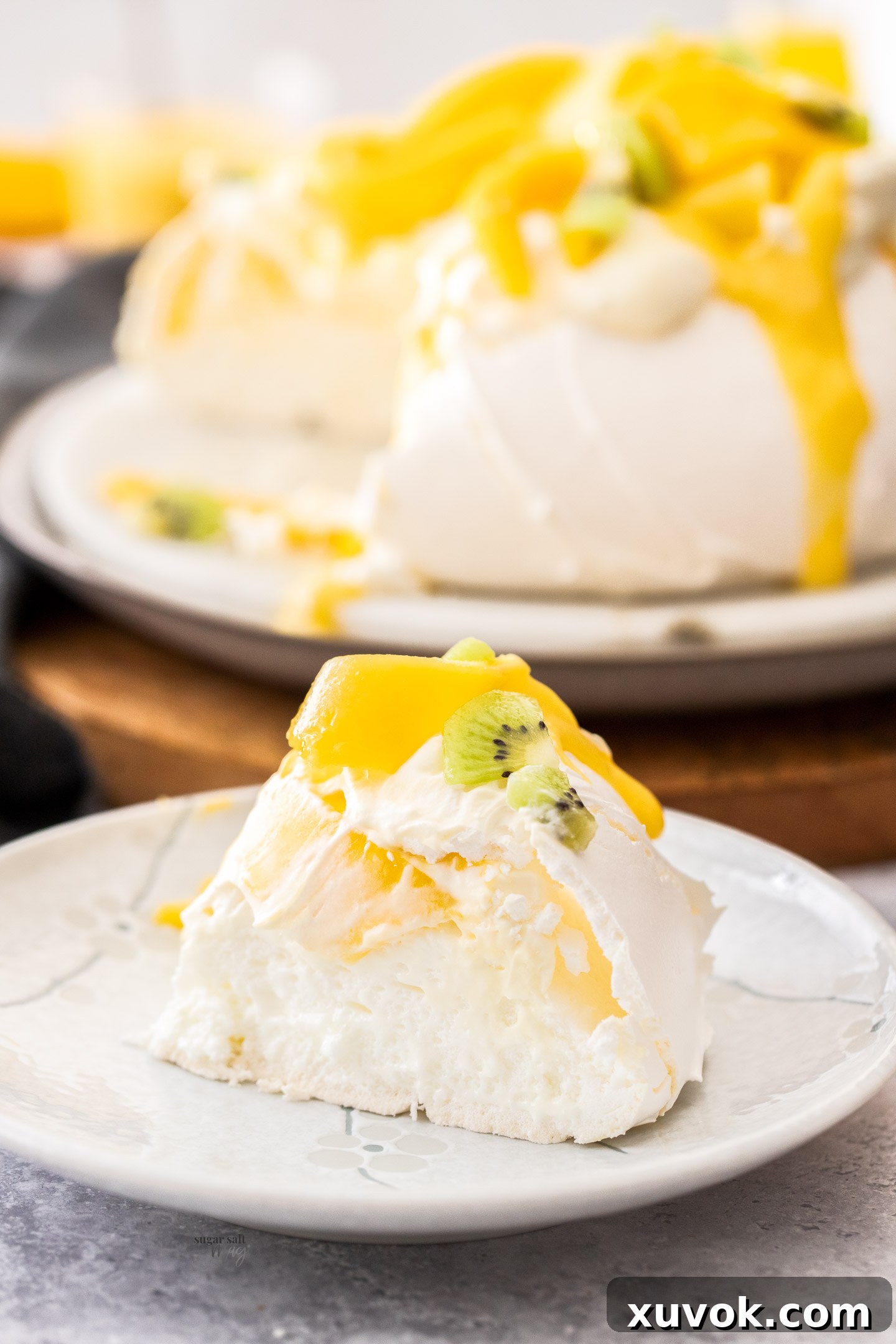 A slice of pavlova, topped with mango and kiwi fruit.