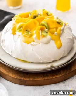 A whole pavlova topped with mango and cream.
