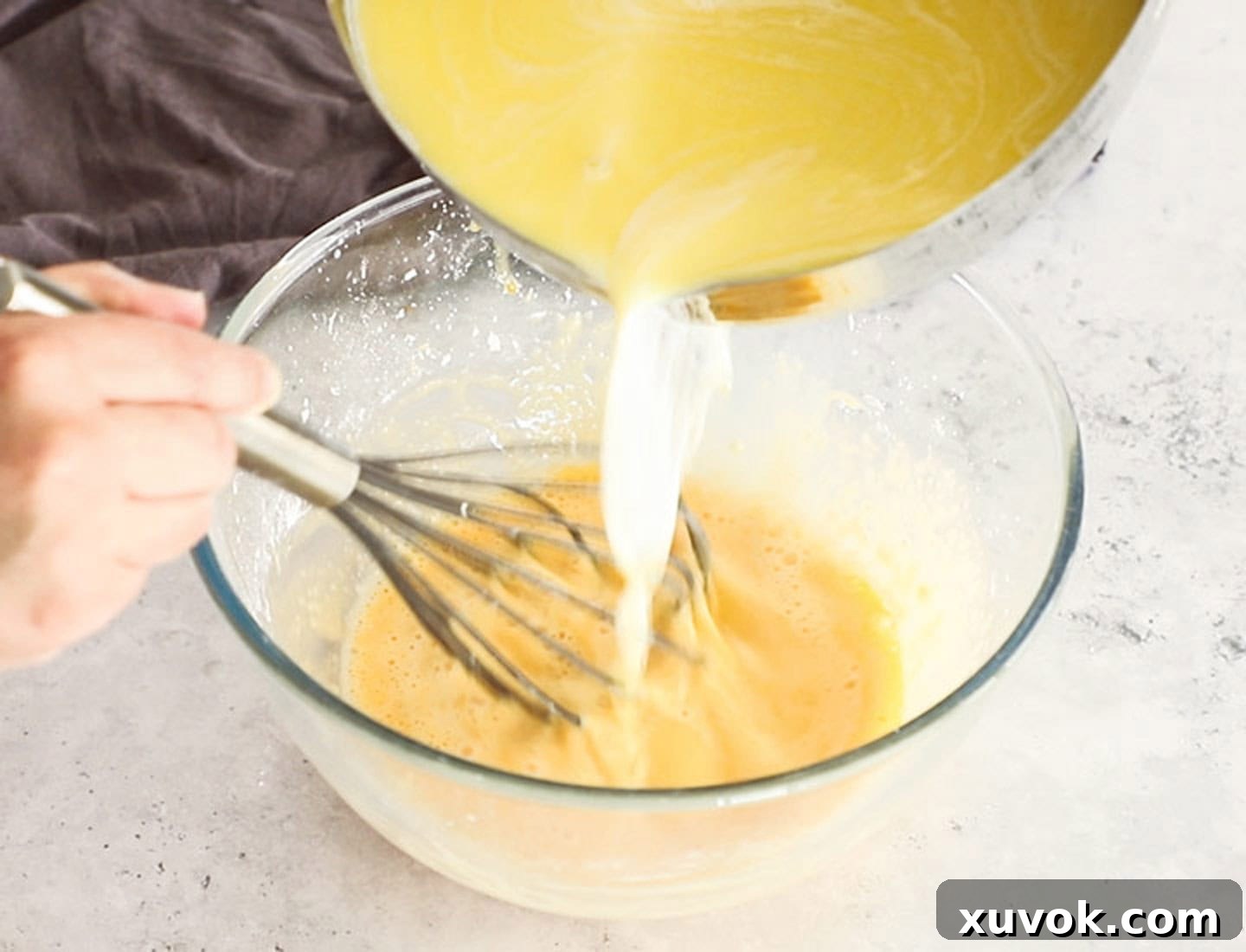 Pouring hot milk and butter into the egg mixture.