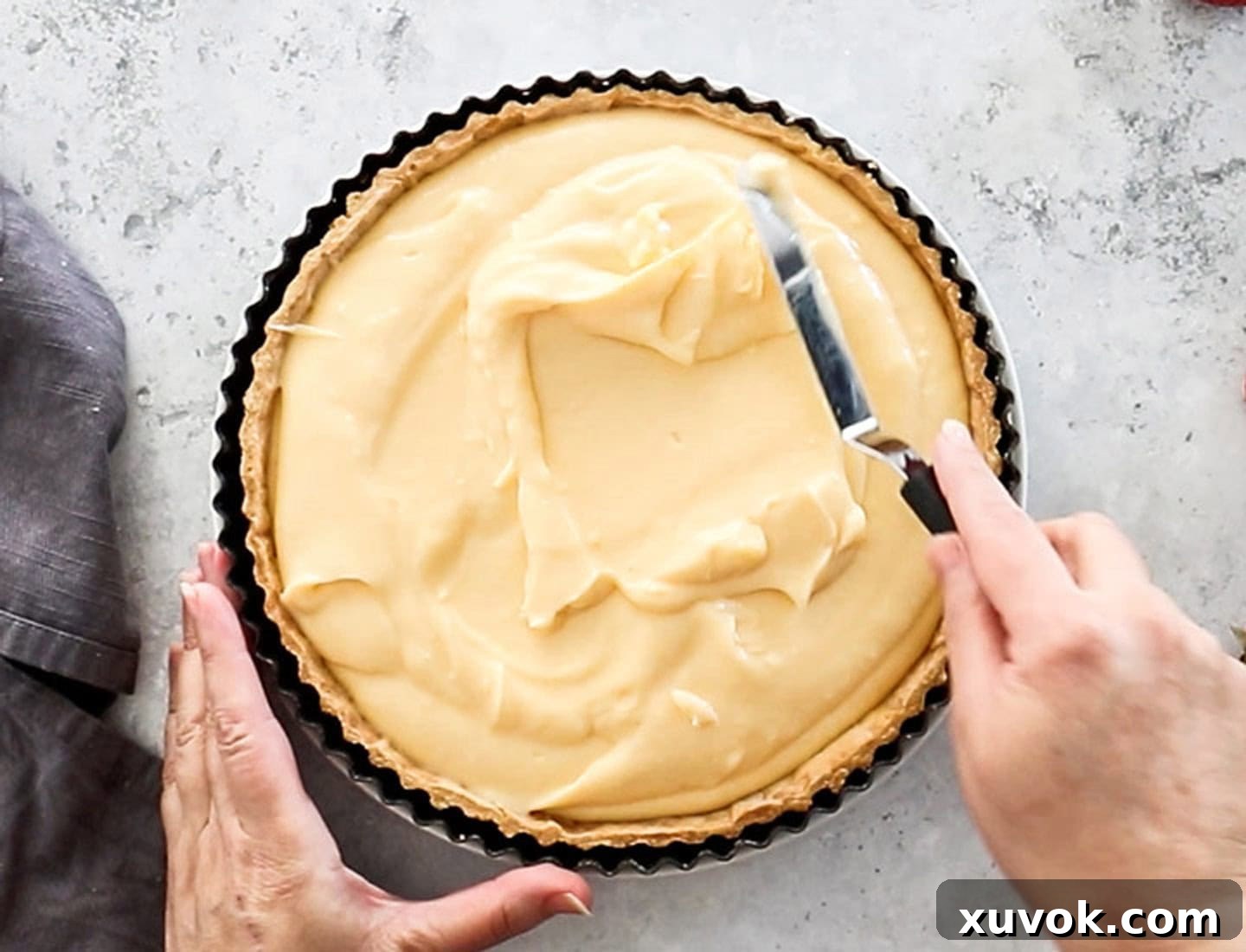 Spreading the thick custard into the tart shell.