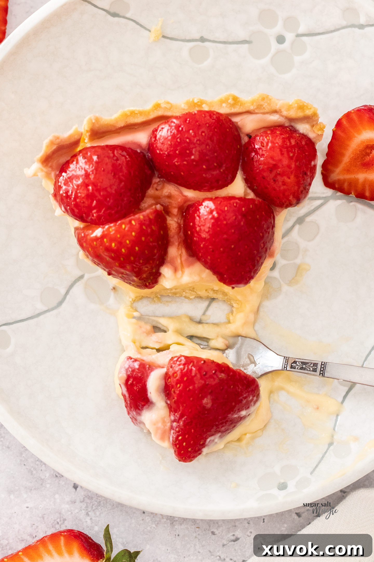 Top down view of a slice of strawberry tart with some cut away.