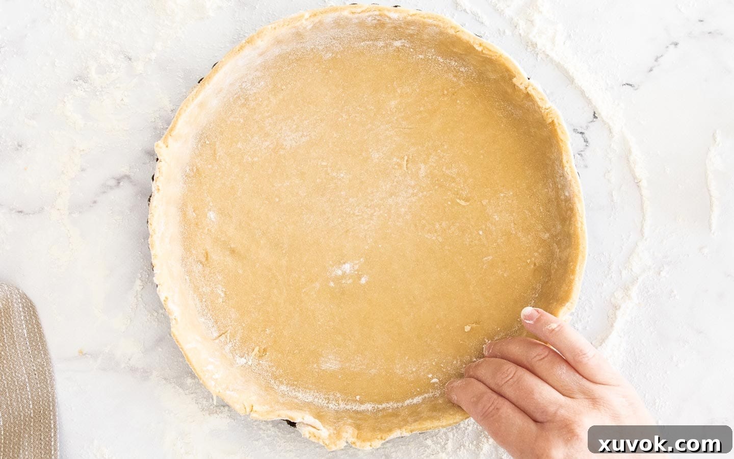 A hand shaping the pastry into the baking pan.