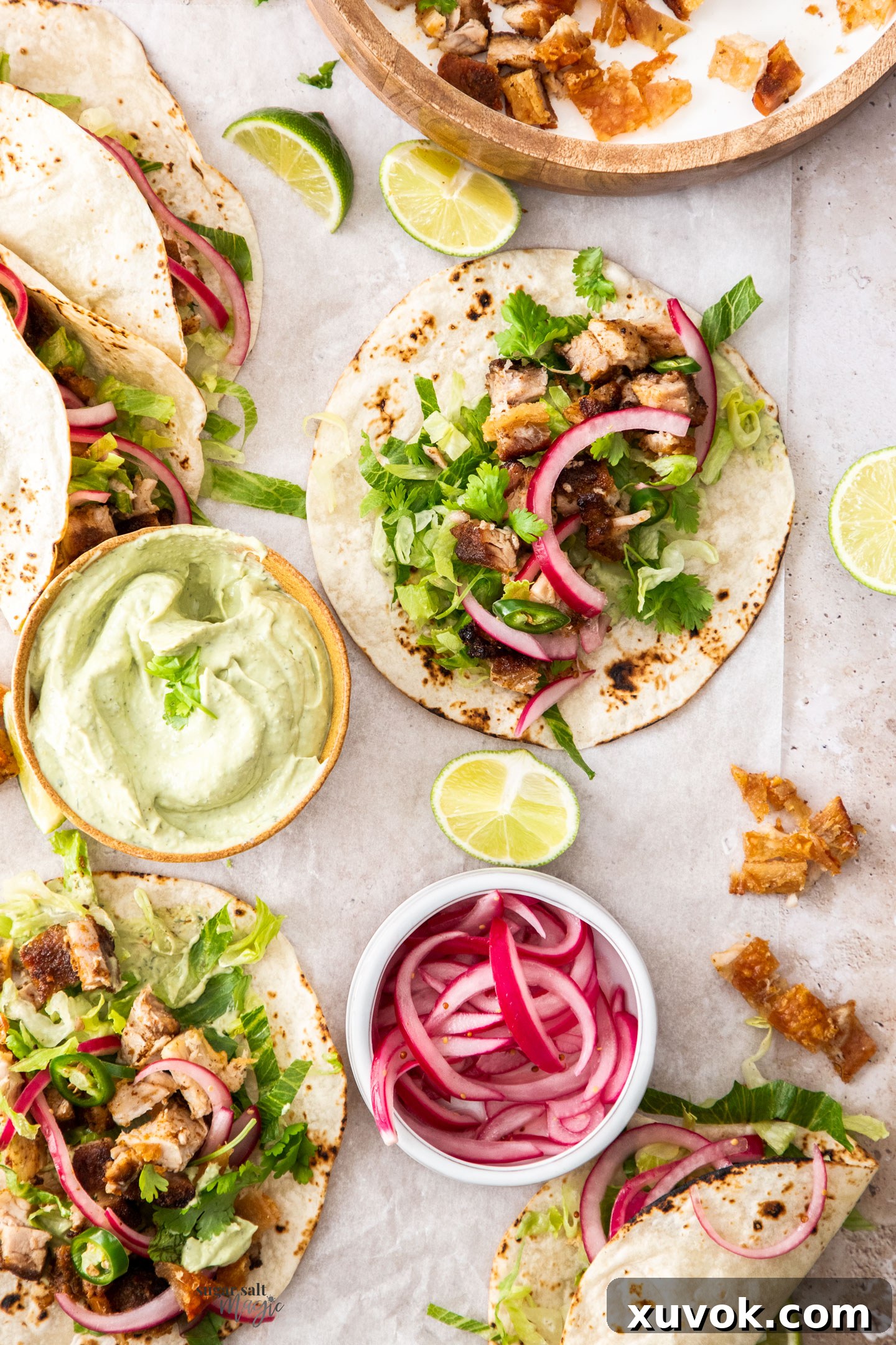 Delicious pork belly tacos filled with shredded lettuce, succulent roast pork, and a generous drizzle of avocado ranch sauce.