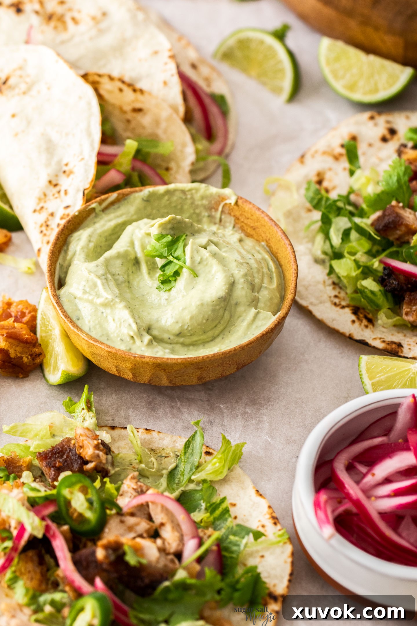 A beautifully presented bowl of creamy, bright green avocado ranch sauce, garnished with fresh herbs, ready to be served with tacos.