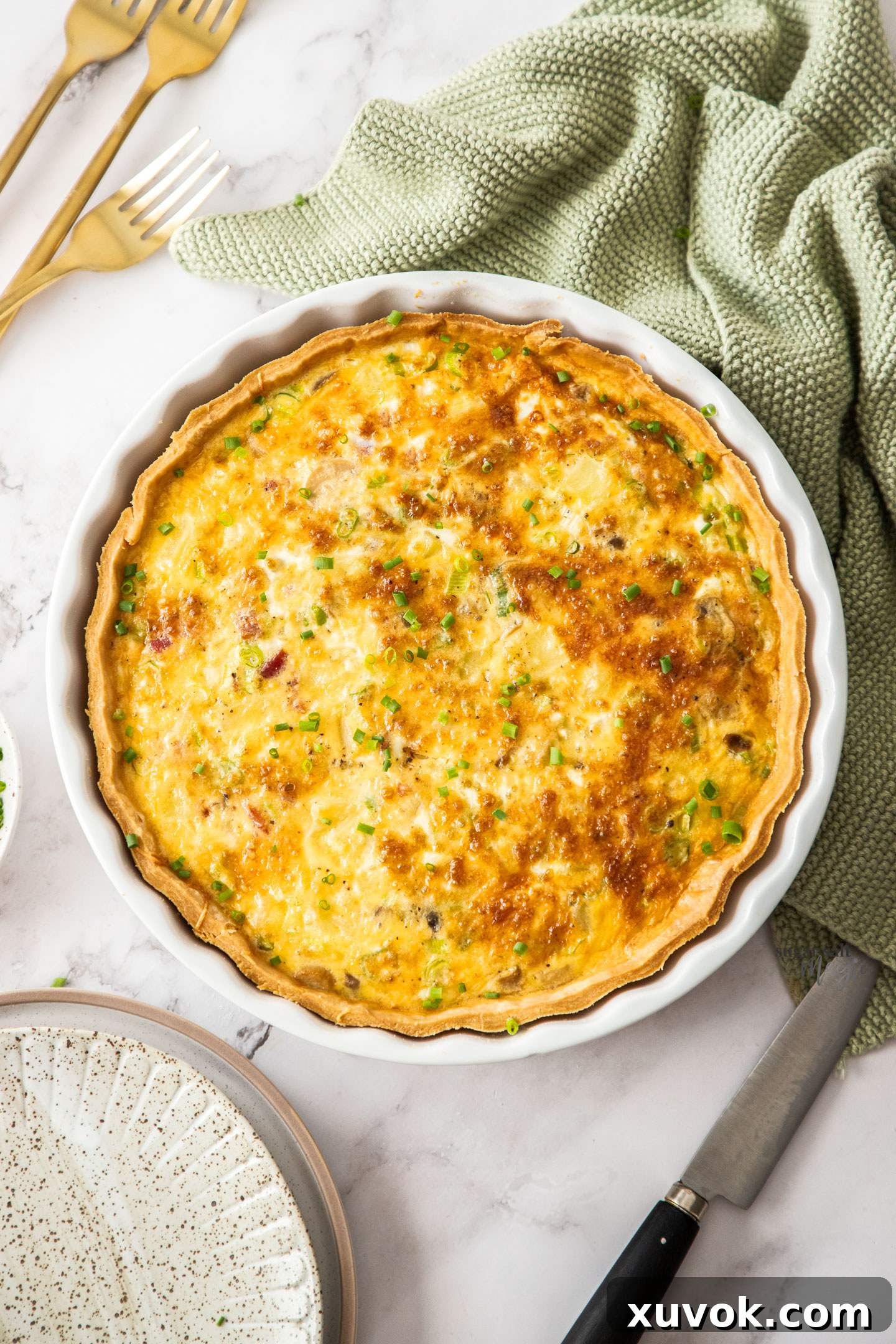 A beautiful top-down view of a golden-brown bacon and potato quiche, freshly baked in a fluted pie dish, highlighting its rustic charm and generous filling, with a perfectly crimped crust.