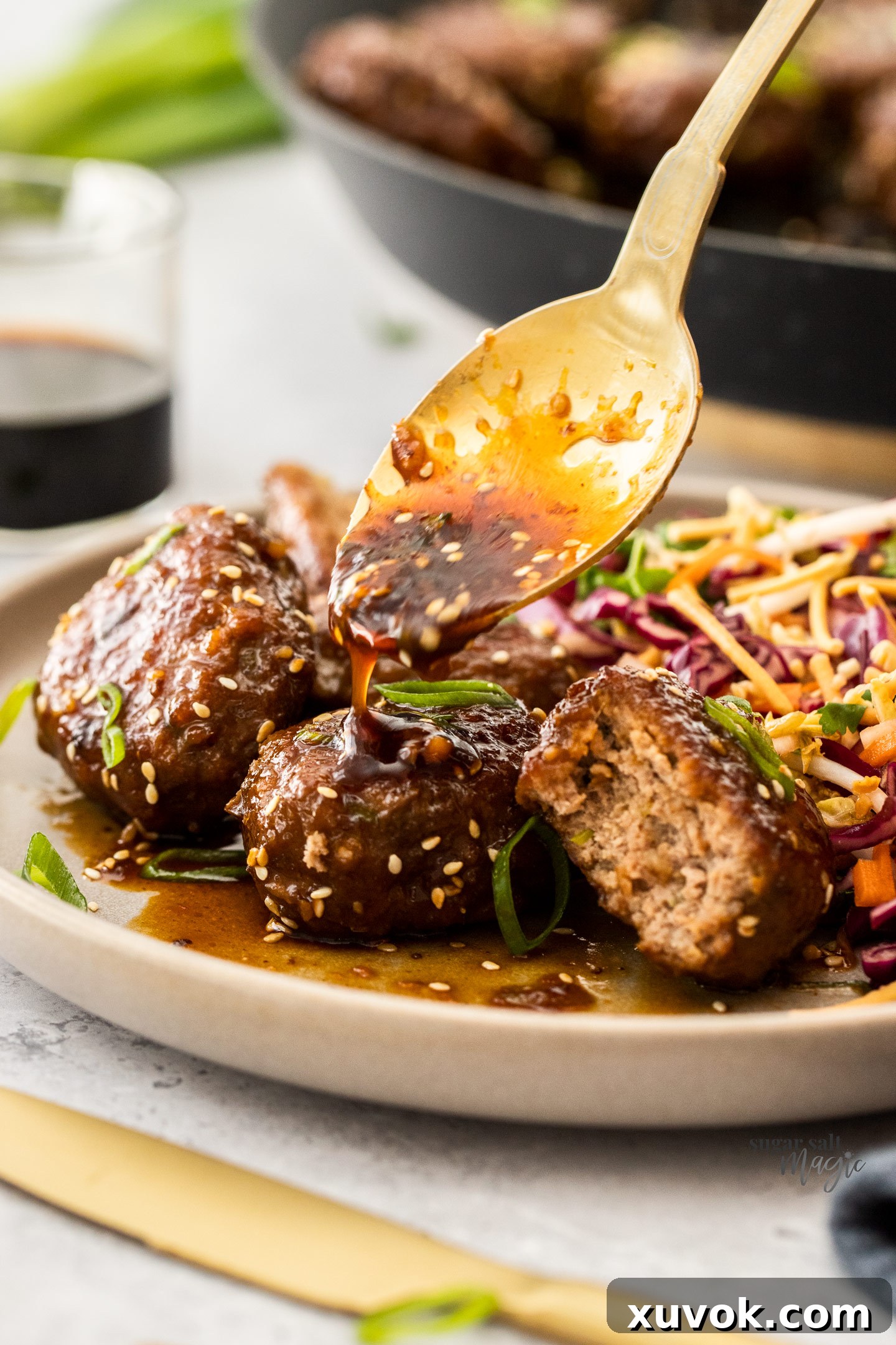 Spooning sauce over turkey rissoles on a plate.