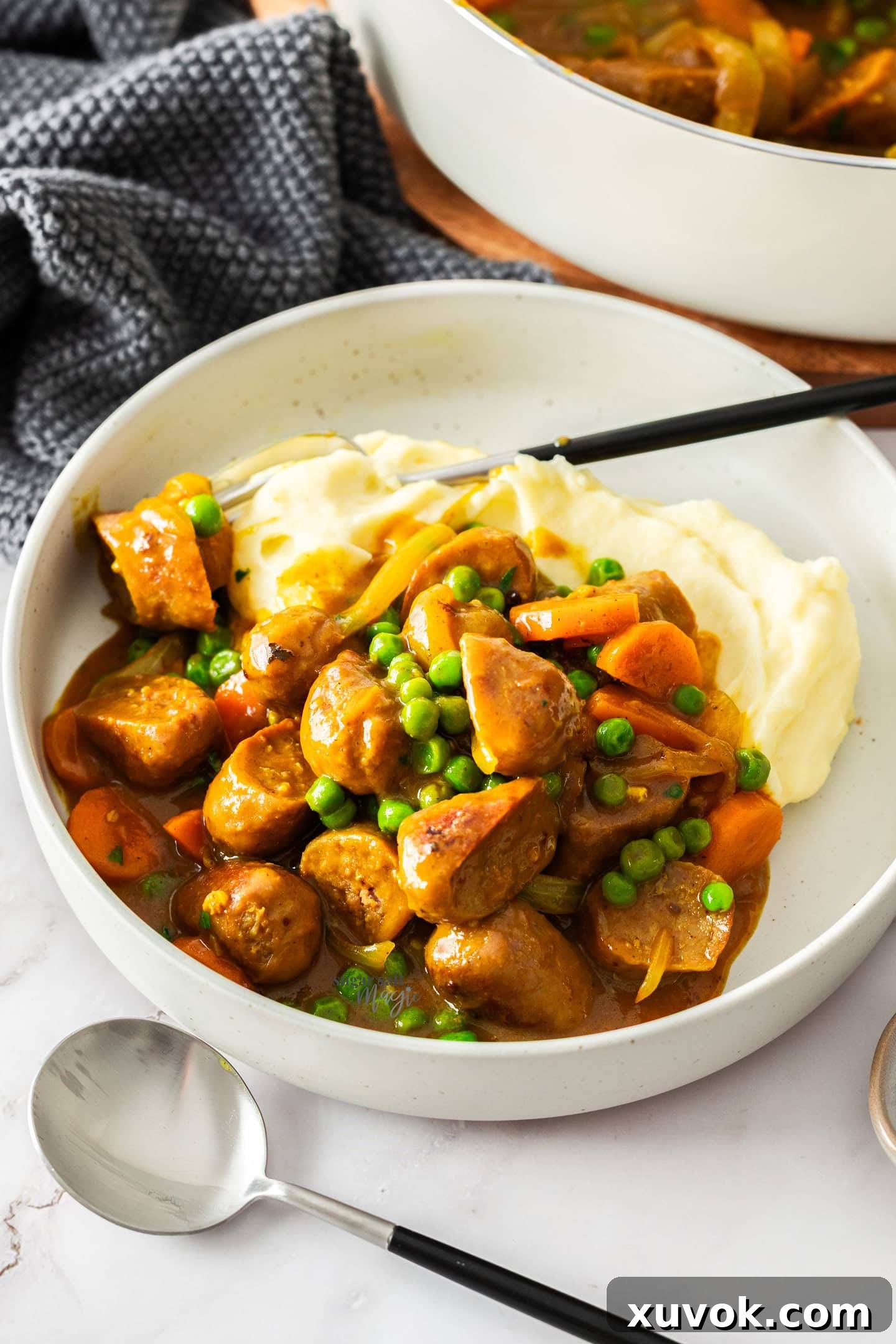 Curried sausages on top of potato mash in a dinner plate.