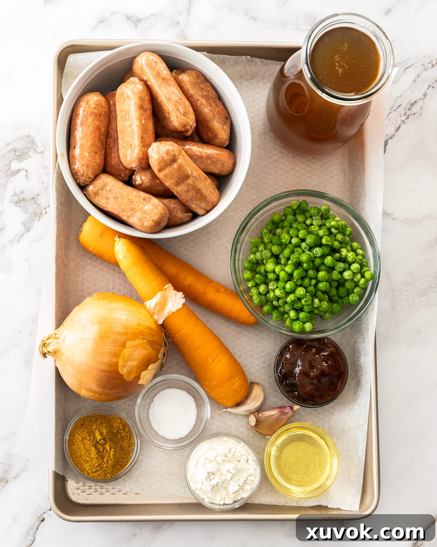 Ingredients for curried sausages on a baking tray.