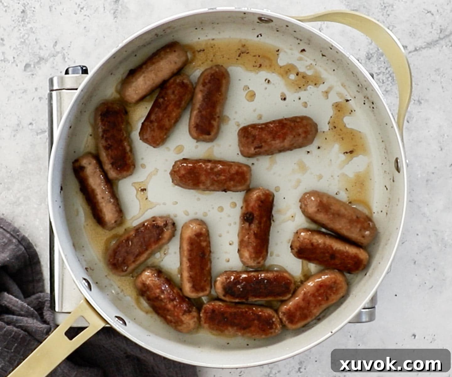 The sausages cooking in a pan.