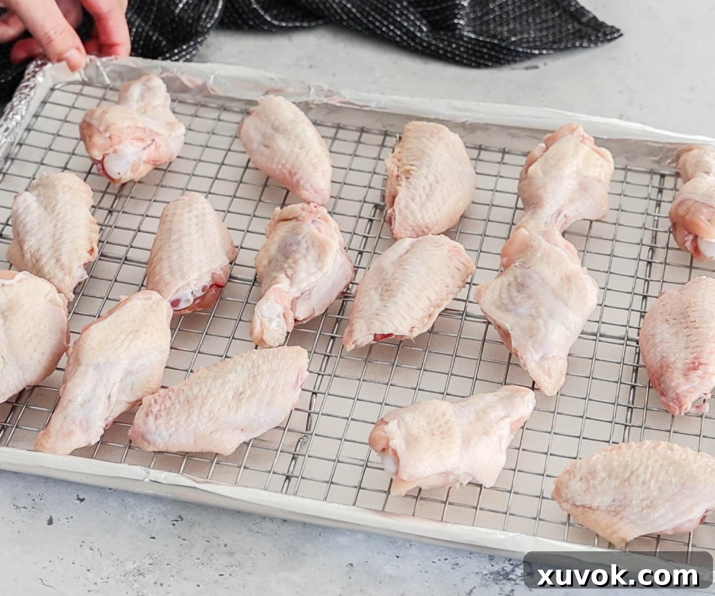 The raw chicken wings on a rack on top of a baking sheet.