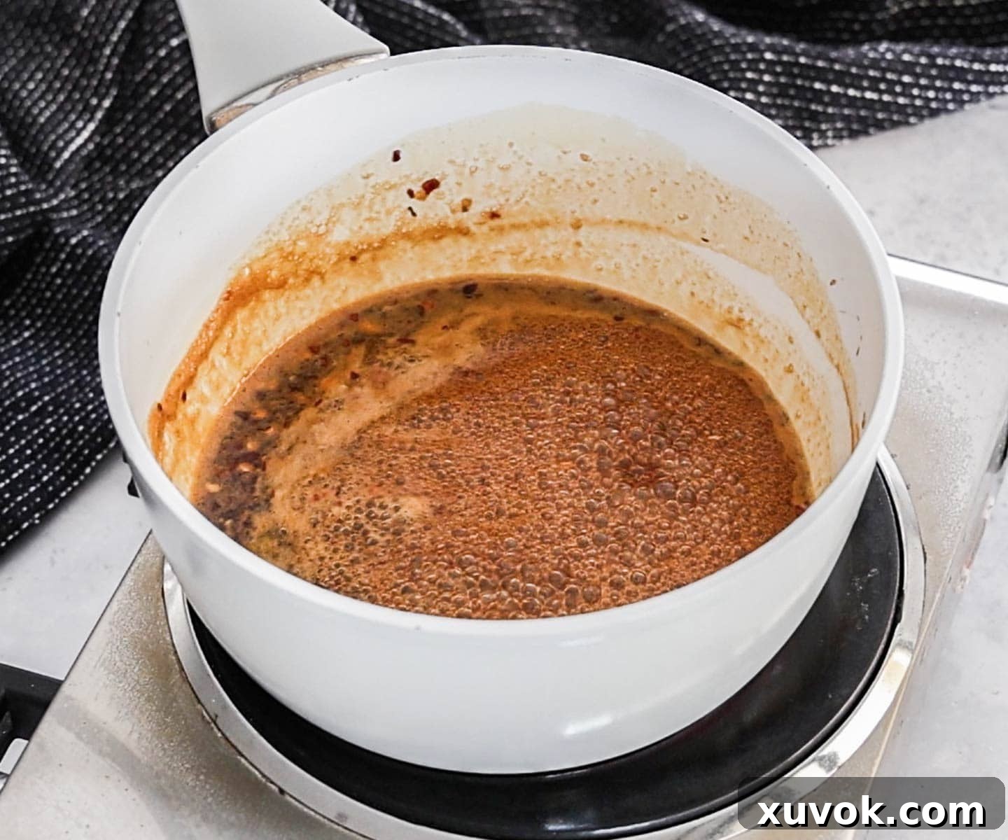 The honey garlic glaze for chicken wings simmering in a saucepan.