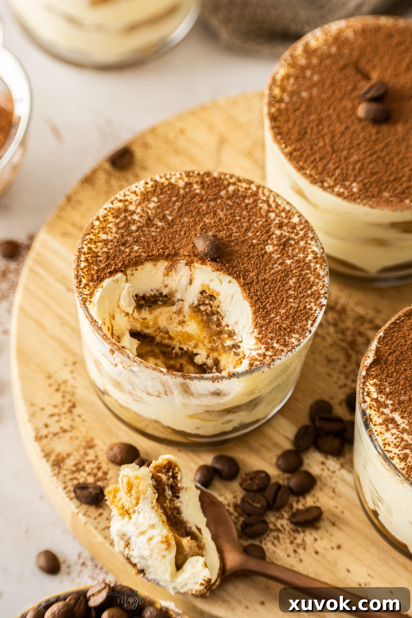 A close-up view looking down into a tiramisu cup, clearly showing the beautifully defined layers of creamy mascarpone, coffee-soaked ladyfingers, and a cocoa dusting.