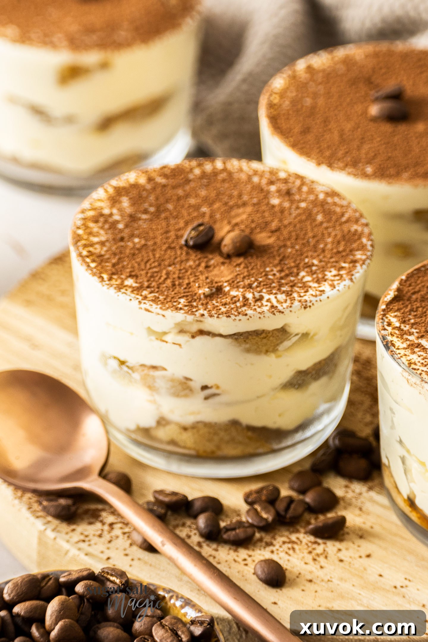 A close-up shot of a single tiramisu cup, highlighting the smooth, creamy top layer and a dusting of rich cocoa powder.